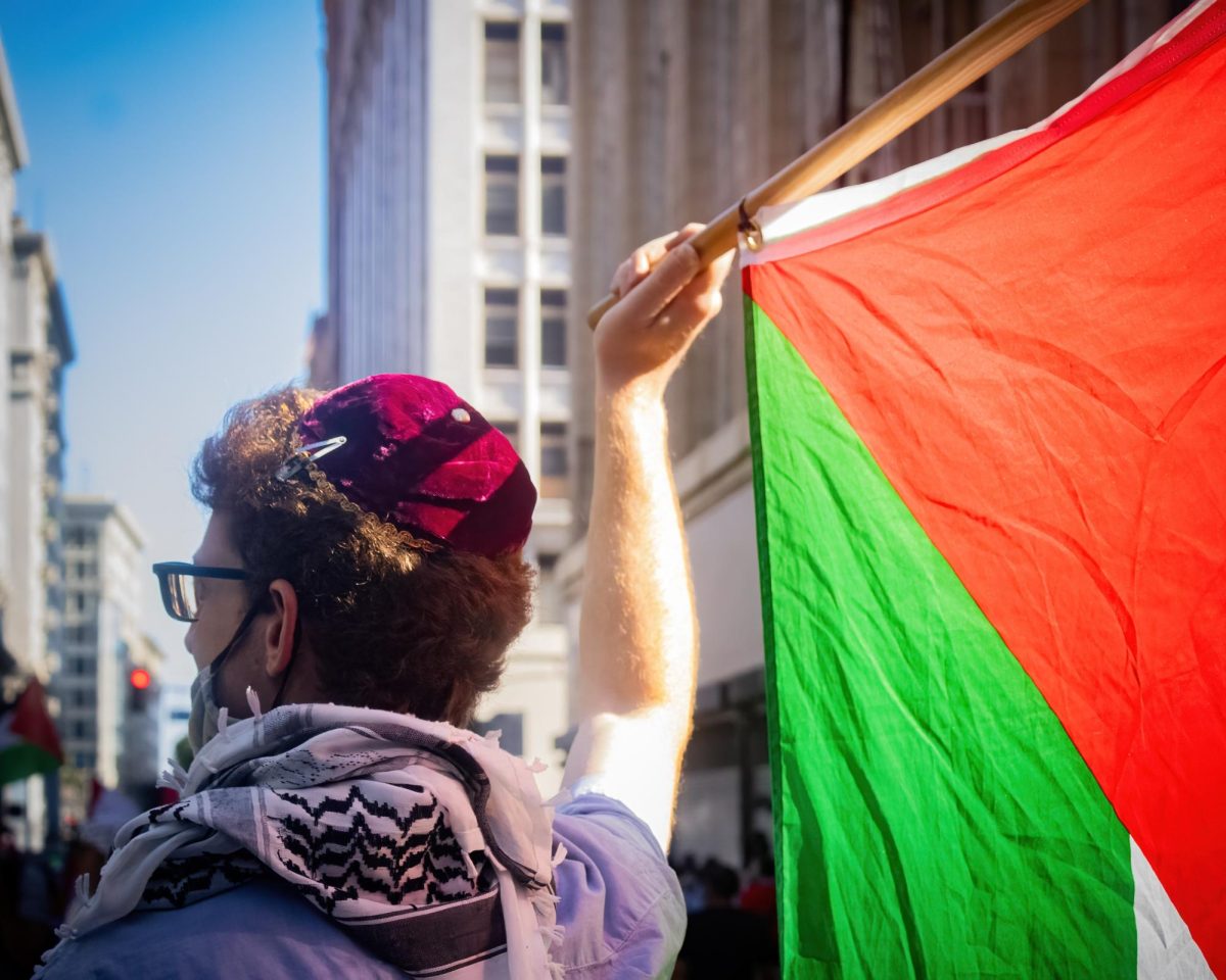 A protestor wearing a kippah holds a Palestinian flag high at a pro-Palestine march in Downtown Los Angeles on Saturday. 