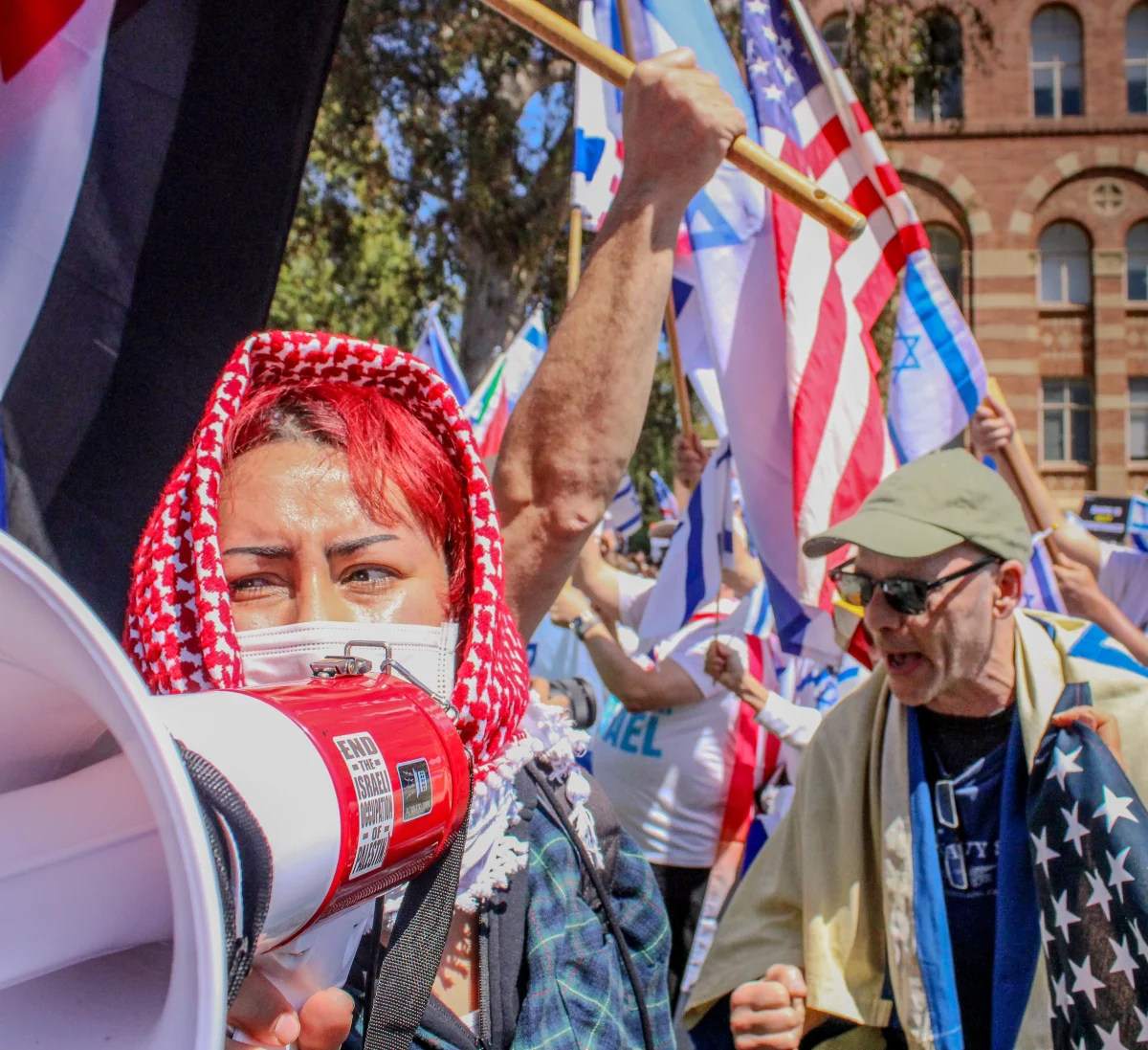 A pro-Palestine protester with a megaphone looks behind her in distress as a man from the pro-Israel side yells at the opposing protesters in front of him. Photo taken at UCLA's Dickson Plaza on Sunday, April 28. 